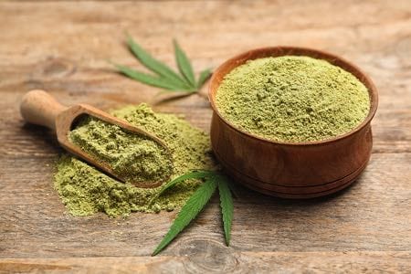 Bowl of Hemp Protein with Hemp Leaves & Wooden Spoon Bowl of hemp protein with two small hemp leaves and a wooden spoon on a wooden table, showcasing natural, plant-based nutrition