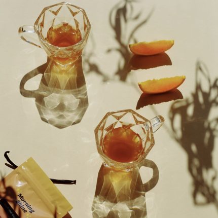 Two cups of Morning Shine Tea with orange slices under bright morning sunlight.