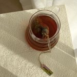 Morning Shine Tea brewing in a glass pot with tea bag steeping in warm sunlight.